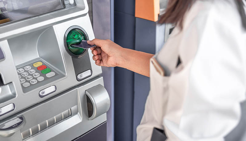 Person inserting debit card into ATM